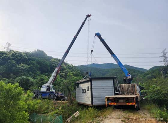 크레인 두 대로 컨테이너 건물을 함께 인양하는 모습